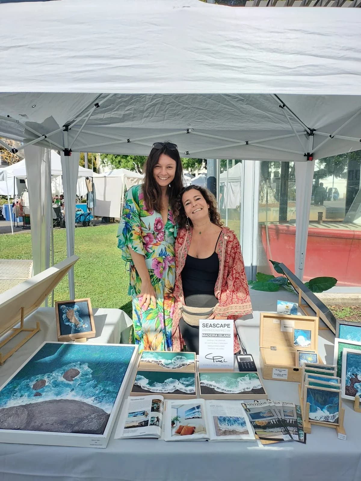 Local artist Carolina Pixel presenting her original textured seascape paintings at an artisan market in Funchal, Madeira.
